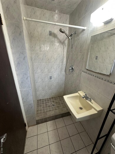 Bathroom featuring tile walls, a shower stall, and light tile patterned floors