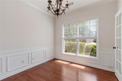 Spare room featuring a chandelier, ornamental molding, dark wood finished floors, a wainscoted wall, and a decorative wall