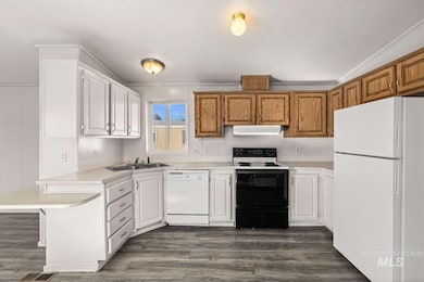 Kitchen with white appliances, light countertops, dark wood-style floors, and lofted ceiling