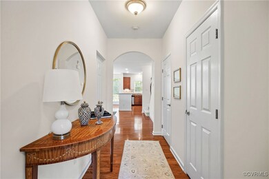 Hallway with arched walkways, baseboards, and dark