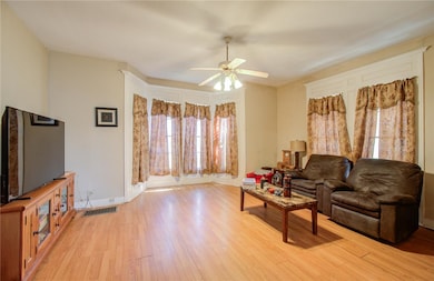 Living room featuring ceiling fan and light wood-t