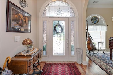 Entryway featuring wood finished floors, crown molding, baseboards, and arched walkways