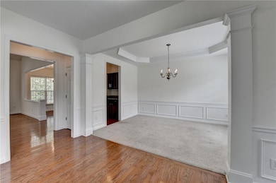 Empty room with a raised ceiling, wainscoting, a c