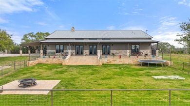 Rear view of house with an outdoor fire pit, a tr