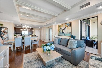 Living room with beam ceiling, hardwood / wood-style floors, ornamental molding, and a notable chandelier