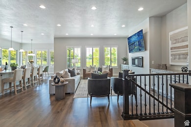 Living room with a textured ceiling, recessed lighting, dark wood finished floors, and a glass covered fireplace