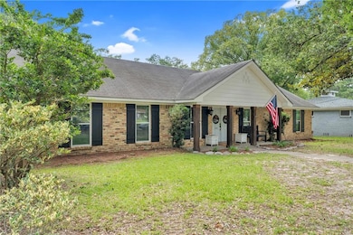 Ranch-style house featuring a front lawn, covered porch, brick siding, and roof with shingles