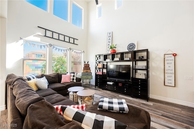 Living room featuring healthy amount of natural light, wood-style floors, and a high ceiling