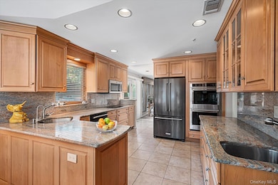 Kitchen with black appliances, recessed lighting, light stone counters, light tile patterned floors, and a peninsula