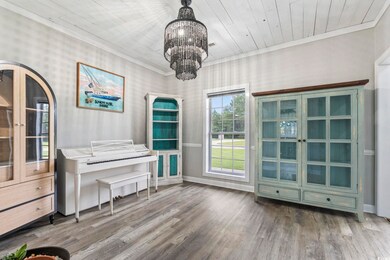 Sitting room with wood finished floors, a chandelier, and ornamental molding