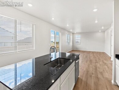 Kitchen with dark stone countertops, white cabinetry, light wood-style flooring, recessed lighting, and stainless steel dishwasher