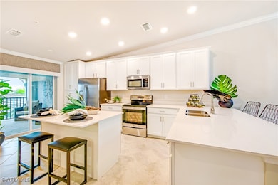 Kitchen with crown molding, white cabinets, a breakfast bar, appliances with stainless steel finishes, and a sink