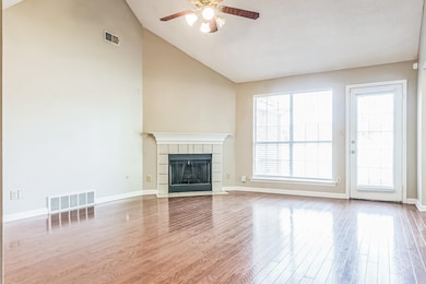 Unfurnished living room featuring ceiling fan, a fireplace, wood finished floors, baseboards, and high vaulted ceiling