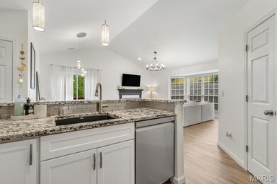 Kitchen featuring vaulted ceiling, white cabinets, dishwasher, light stone countertops, and light wood-type flooring