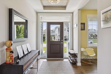 The foyer is a charming guest entryway with a glass surround and overhead light in a tray ceiling.