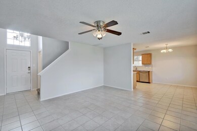 Unfurnished living room with a chandelier, light tile patterned floors, a textured ceiling, a ceiling fan, and stairway