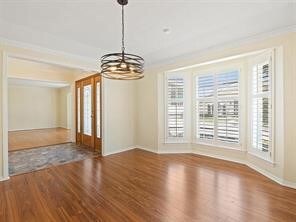 Unfurnished dining area featuring plenty of natural light, dark wood finished floors, and a chandelier