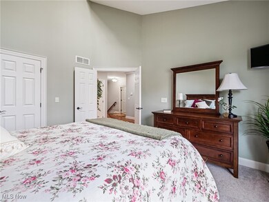 Carpeted bedroom with a high ceiling and baseboards