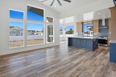 Kitchen featuring backsplash, wall chimney exhaust hood, blue cabinets, stainless steel electric range, and dark wood-type flooring