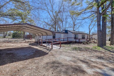 Back of property featuring a carport and a wooden 