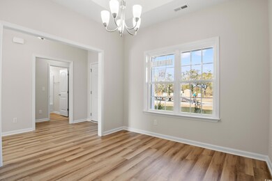 Empty room with a chandelier and light hardwood / 
