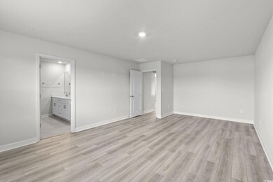 Unfurnished bedroom with light wood-style floors and connected bathroom