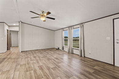 Unfurnished living room featuring light wood-type flooring, lofted ceiling, ceiling fan, and crown molding