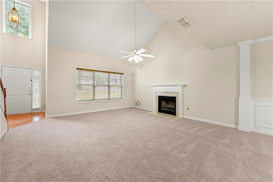 Unfurnished living room with high vaulted ceiling, light colored carpet, a fireplace with flush hearth, stairs, and ceiling fan