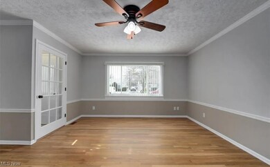 Family room with ornamental molding, light hardwood / wood-style floors, a textured ceiling, and ceiling fan