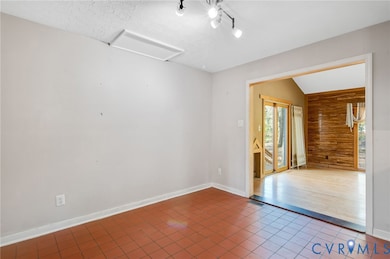 Spare room with tile patterned flooring, vaulted ceiling, a textured ceiling, and attic access