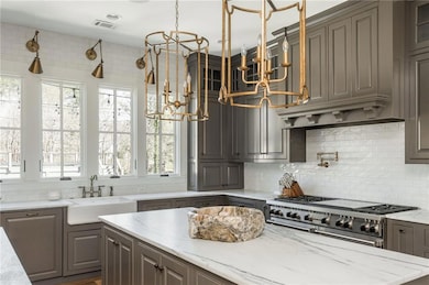 Custom kitchen with double islands, designer light fixtures, Wolf appliances, stone countertops, and hardwood floors