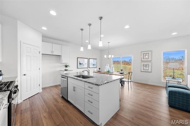 Kitchen with white cabinetry, light stone counters, recessed lighting, a chandelier, and pendant lighting