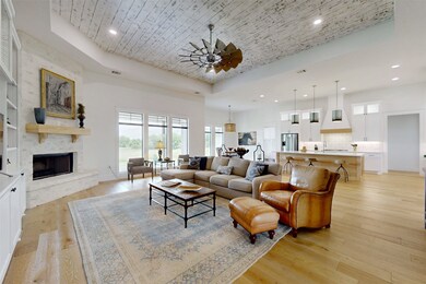 Living room featuring a raised ceiling, recessed lighting, light wood finished floors, a fireplace, and wooden ceiling