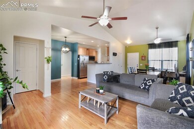 Living room with high vaulted ceiling, light wood-type flooring, baseboards, and ceiling fan with notable chandelier