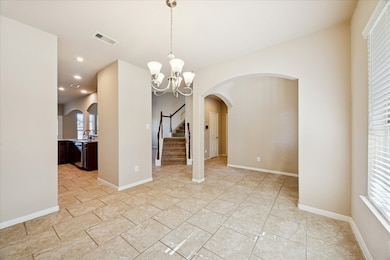 This inviting home features a spacious entryway with elegant tile flooring and neutral walls. A stylish chandelier adds warmth, while arched doorways lead to a cozy kitchen and dining area. A staircase in the background provides easy access to the upper level, enhancing the home's open and airy feel.