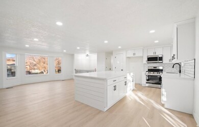 Kitchen with stainless steel appliances, white cabinetry, a center island, open floor plan, and tasteful backsplash