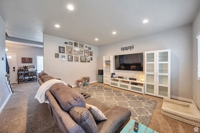 Carpeted living area featuring recessed lighting and baseboards