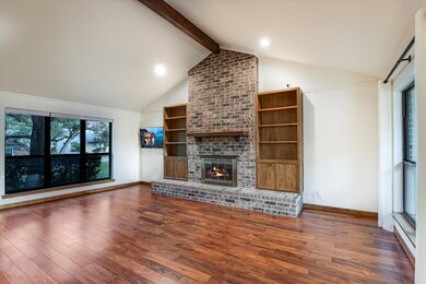 Unfurnished living room with dark wood-type flooring and a brick fireplace