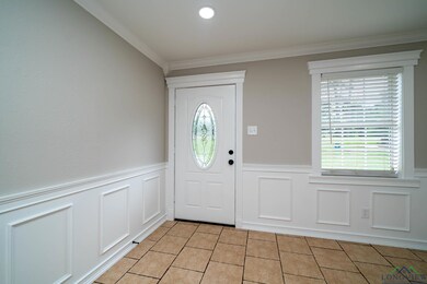 Entryway featuring a wainscoted wall, light tile patterned floors, and a wealth of natural light