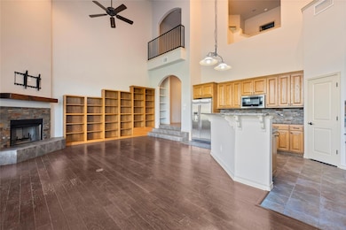 Kitchen with a kitchen breakfast bar, light stone countertops, a high ceiling, open floor plan, and stainless steel appliances