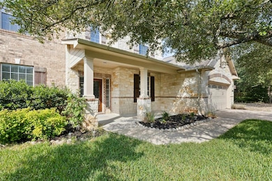 View of front of home with stone siding, a garage, covered porch, and driveway