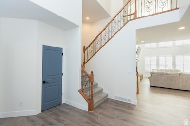 Stairs with wood finished floors, recessed lighting, and a towering ceiling