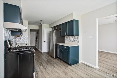 Kitchen with black gas range, freestanding refrigerator, light wood-style floors, and backsplash