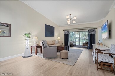 Living area featuring lofted ceiling, ornamental molding, light wood-type flooring, a chandelier, and baseboards