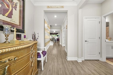Hallway with ornamental molding, light wood finished floors, and recessed lighting