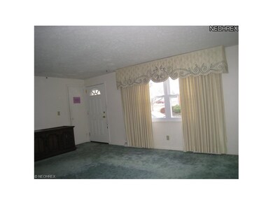 Alternate view of the living room shows the cloak closet, newer entry door and newer vinyl windows.