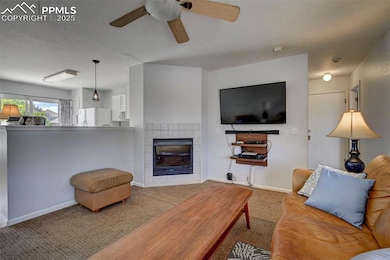Living area with carpet floors, a fireplace, and ceiling fan