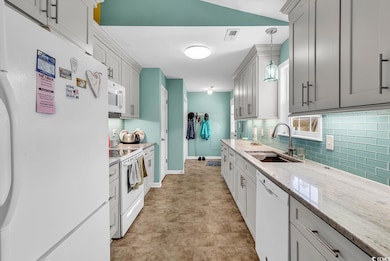 Kitchen with white appliances, a sink, backsplash,