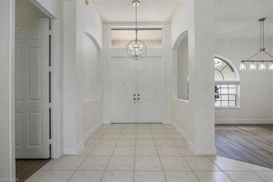 Foyer with a chandelier, light tile patterned flooring, and arched walkways