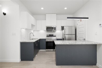 Kitchen with tasteful backsplash, sink, appliances with stainless steel finishes, light stone counters, and white cabinets